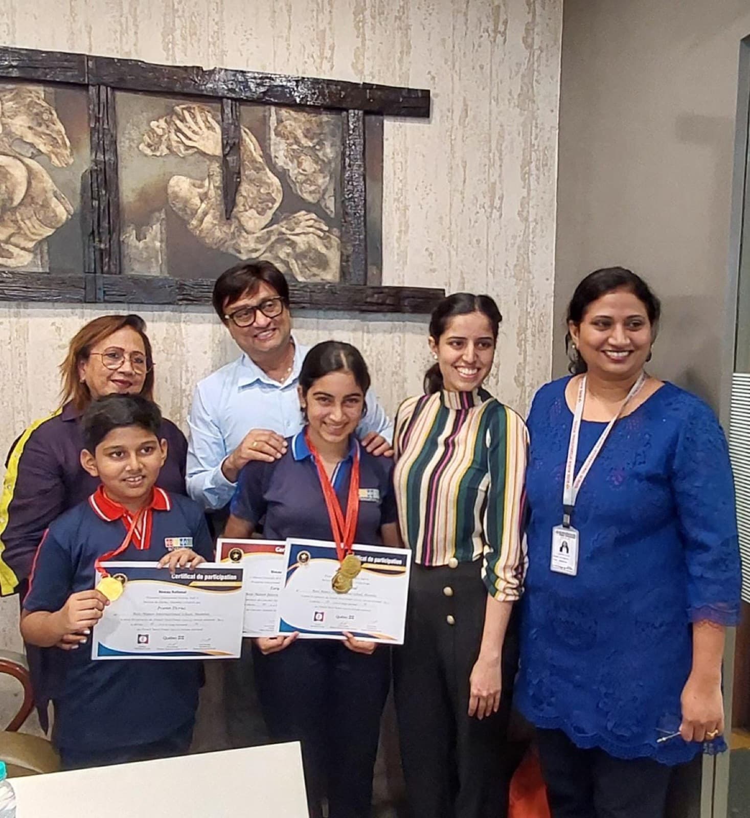 Two school students holding Certificat de participation and wearing medals, with their teachers