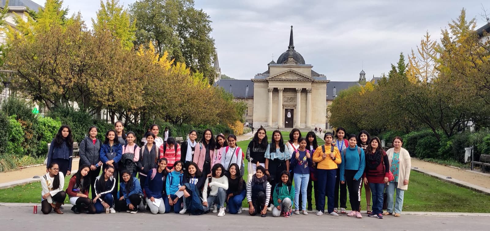 Students from India outside a neoclassical building among autumn trees during the immersion programme in France